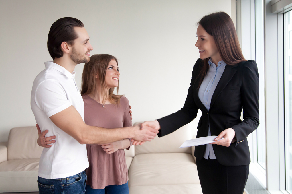 Smiling couple shaking hands with realtor